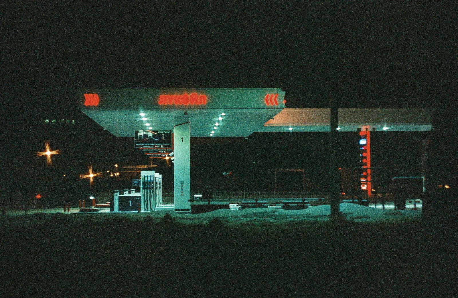 A dark gas station bathed in neon light